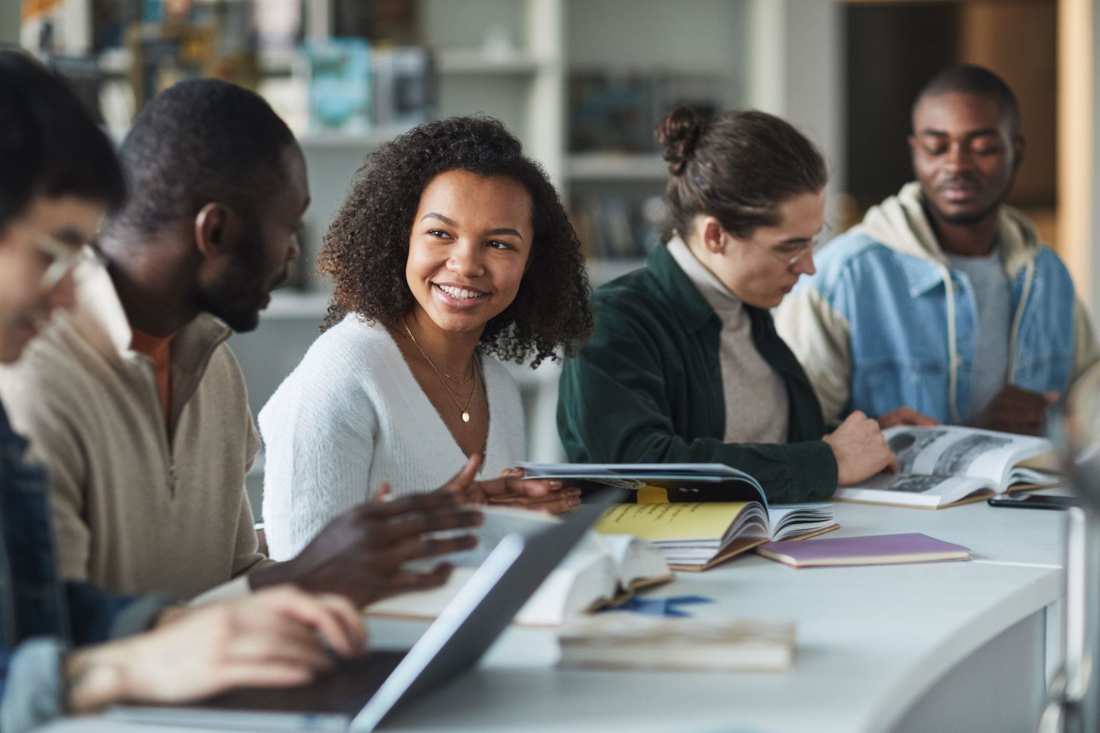 A diverse group of young adults studying together in a library, fostering teamwork and learning.